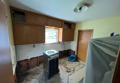 A dehumidifier and an air mover drying a kitchen after the lower cabinets and wall bottoms were taken out