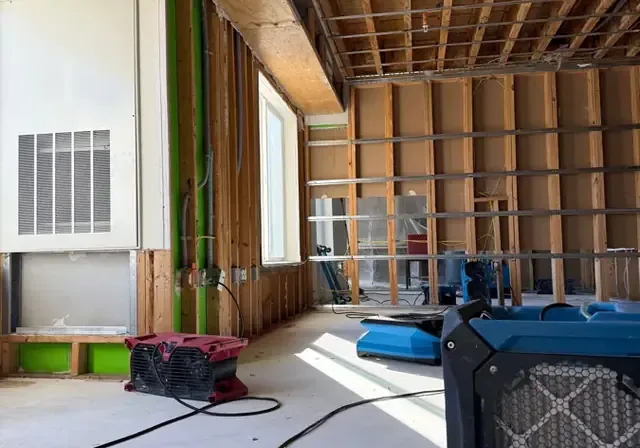 Air movers and an air scrubber drying a room opened down to the studs and ceiling joists