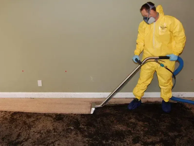 A technician in a protective suit and respirator extracting a sewage backup